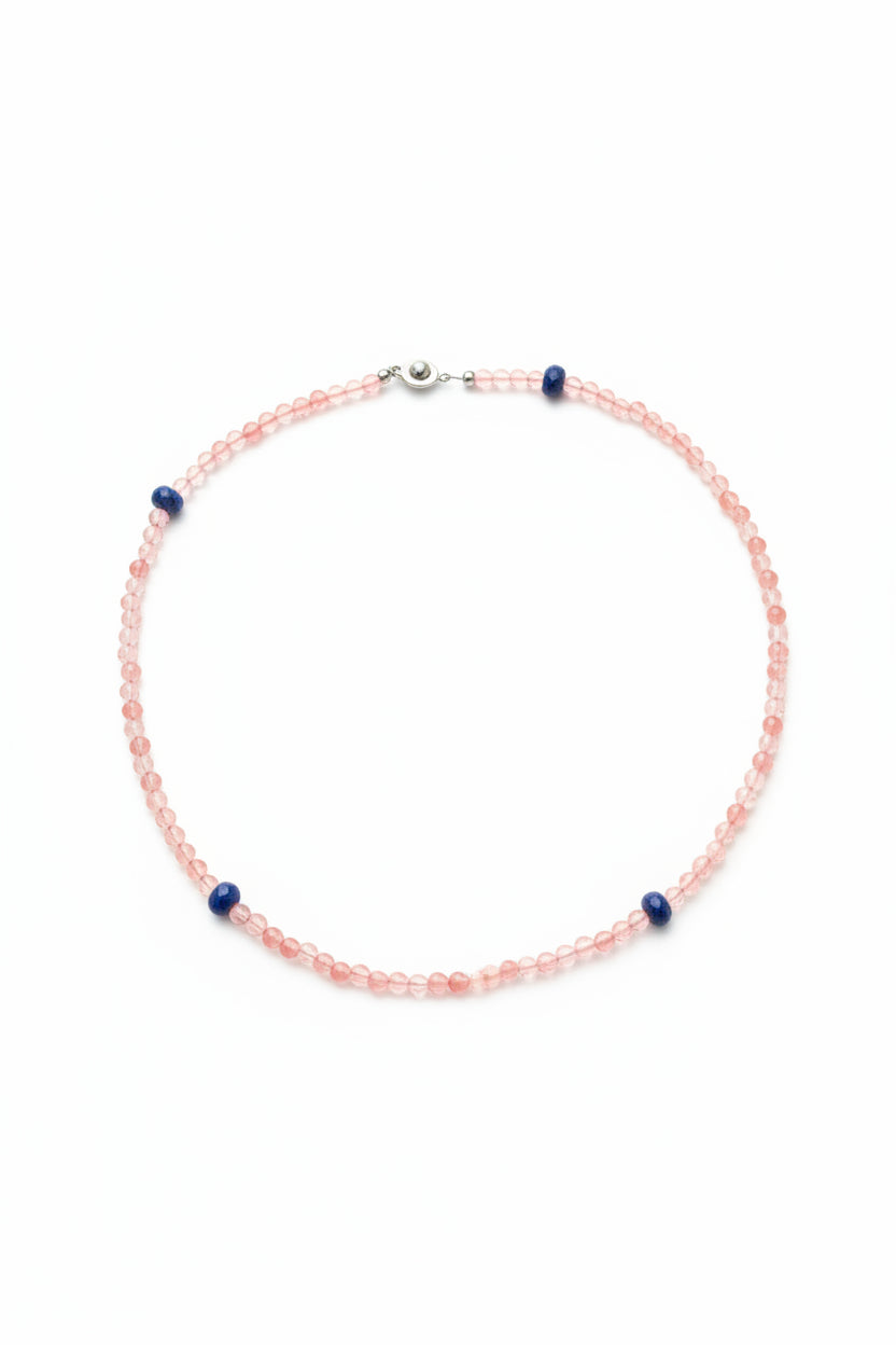 A beaded necklace made of small pink faceted beads with a few blue spacer beads and a silver clasp, laid flat on a white background.